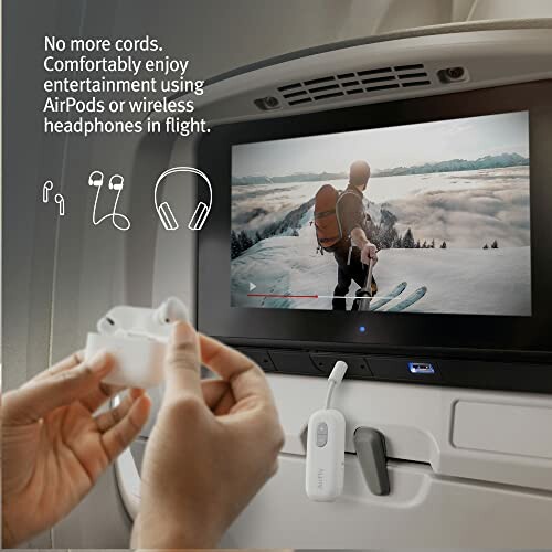 Person holding AirPods near airplane screen displaying a skier.