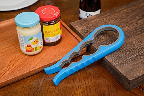 Jar opener next to jars on a wooden surface.