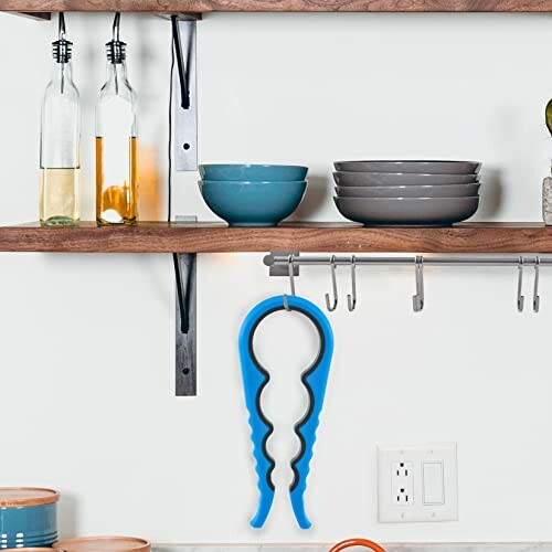 Kitchen shelf with bowls and a blue jar opener hanging.