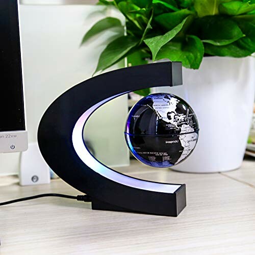 Levitating globe with black stand on desk near plant