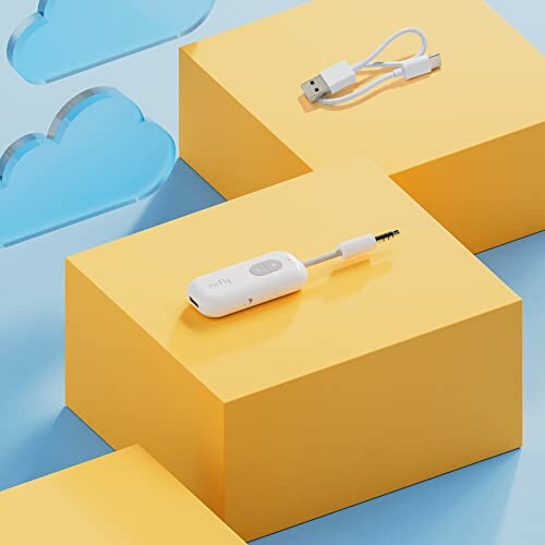 Wireless audio transmitter and USB cable on yellow blocks.